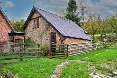 an old brick house with a wooden fence at Finest Retreats - Great Cantal Granary in Llandrindod Wells