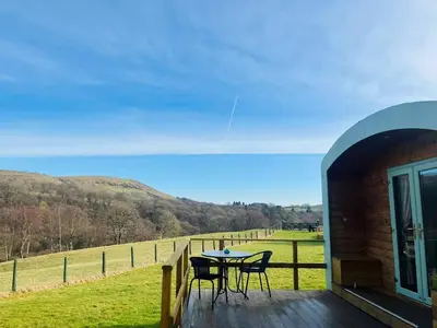a table and chairs on a deck with a view of a field at Hwyl in Abbey-Cwmhir
