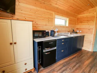 a kitchen with blue cabinets and a sink in a cabin at Hwyl in Abbey-Cwmhir