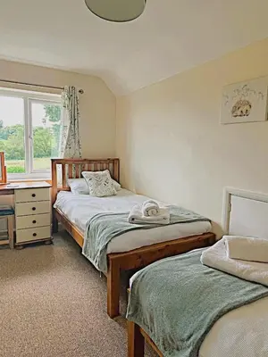 a bedroom with two beds and a desk and a window at Lower Pentre in Llanddewi Ystradenny