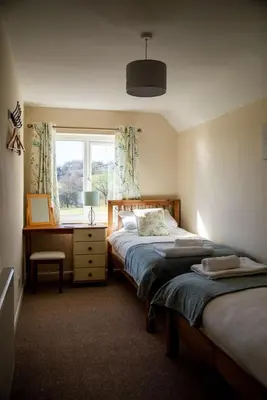 a bedroom with two beds and a desk and a window at Lower Pentre in Llanddewi Ystradenny