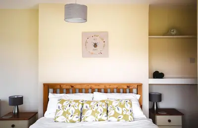 a bedroom with a bed with two night stands and two lamps at Lower Pentre in Llanddewi Ystradenny