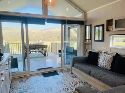 a living room with a couch and a view of a deck at Meadow Retreat in Rhayader