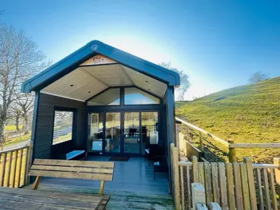 a small cabin with a bench on a wooden deck at Meadow Retreat in Rhayader