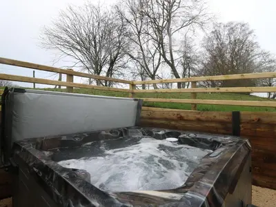 a hot tub with water in it next to a fence at Oak Tree View in Nantmel