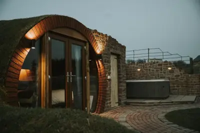a brick house with an arched doorway and a tub at Otters View in Rhayader