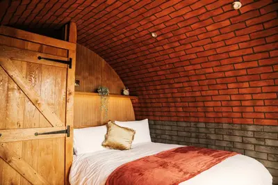 a bedroom with a bed and a brick wall at Otters View in Rhayader