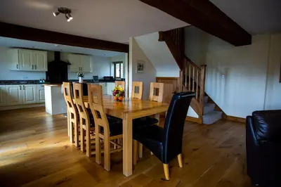 a kitchen and dining room with a wooden table and chairs at Pentre Fawr in Llanddewi Ystradenny
