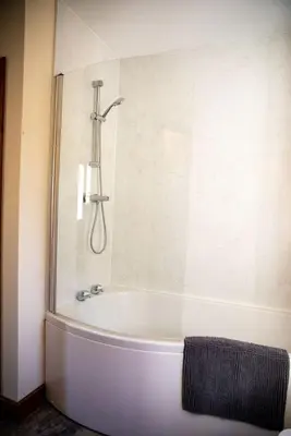 a bath tub in a bathroom with a shower at Pentre Fach in Llanddewi Ystradenny