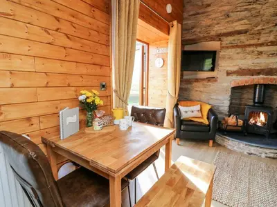 a wooden room with a table and a fireplace at Tegfan Barn in Pant-y-dwr