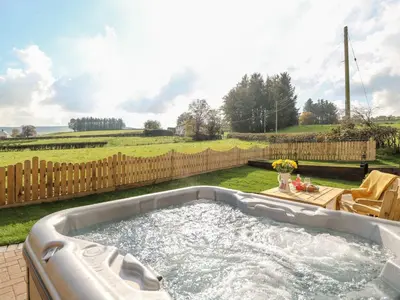 a hot tub in a yard with a fence at Tegfan Barn in Pant-y-dwr