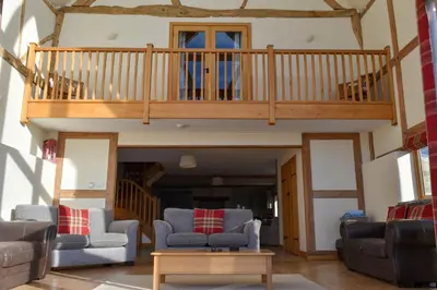 a living room with couches and a wooden staircase at The Hayloft in Knighton