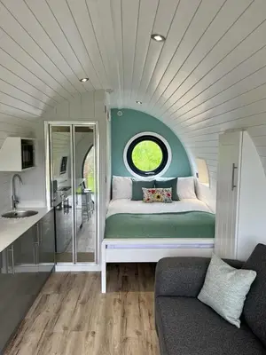 a room with a bed with a window and a kitchen at Y Dderwen in Oswestry