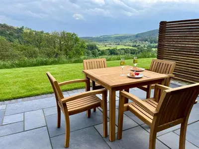 a wooden table with two chairs and two glasses of wine at Y Dderwen in Oswestry