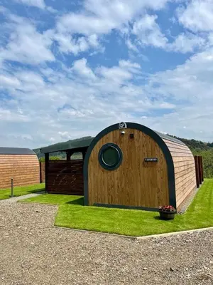 a wooden building with a window in the grass at Y Dderwen in Oswestry