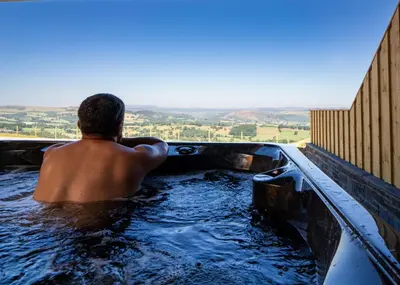 a man sitting in a bath tub in a pool of water at Mountain View in Llanfair Caereinion