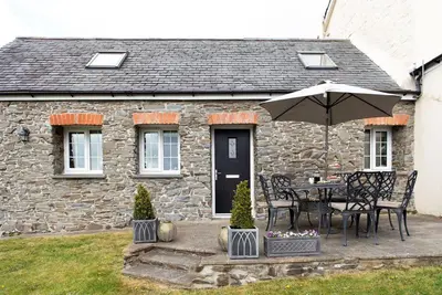 a stone house with a table and an umbrella at Yr Hen Beudy in Aberystwyth
