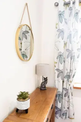 a cat sitting on a wooden table in a room with a mirror at Yr Hen Beudy in Aberystwyth