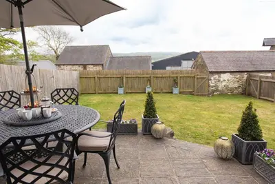 a patio with a table and an umbrella at Yr Hen Beudy in Aberystwyth