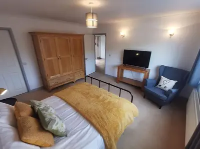 a bedroom with a bed and a chair and a television at Twyngaer, a spacious 3 bedroom bungalow sleeps 5 in Knighton
