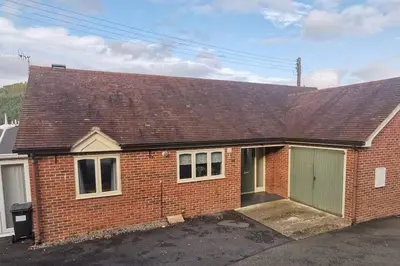 a red brick house with a green garage at Twyngaer, a spacious 3 bedroom bungalow sleeps 5 in Knighton