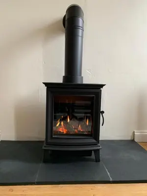 a black stove with a fire in a room at St Milburga Chapel in Stoke Saint Milborough