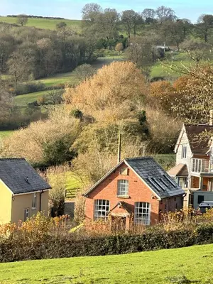 a group of houses in a green field at St Milburga Chapel in Stoke Saint Milborough