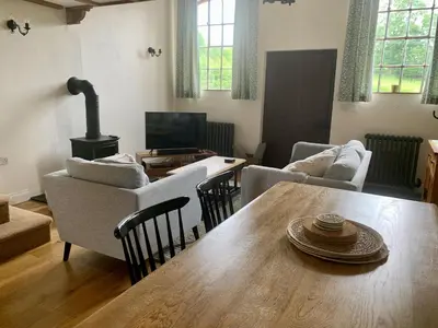 a living room with a table and chairs and a television at St Milburga Chapel in Stoke Saint Milborough