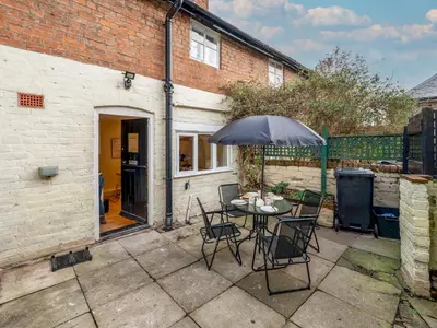 a patio with a table and chairs and an umbrella at Cosy 2 bedroom Victorian Cottage - Pass the Keys in Ludlow