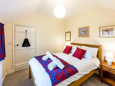 a bedroom with a large white bed with red pillows at Cosy 2 bedroom Victorian Cottage - Pass the Keys in Ludlow