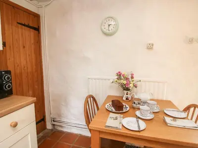 a dining room table with a cake and a clock on the wall at Walkmill Barn in Bishops Castle