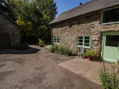 a stone house with a chair in front of it at Walkmill Barn in Bishops Castle