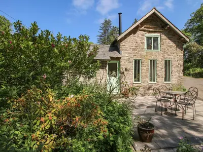 a stone house with a table and chairs in front of it at Walkmill Barn in Bishops Castle