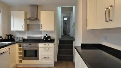 a kitchen with white cabinets and a staircase in the background at Abbey Foregate in Shrewsbury