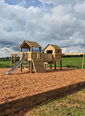 a wooden playground with a slide in a field at Buttercup in Rhayader