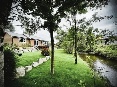 a house with a yard with a river and trees at Ger Yr Afon in Saint Harmon