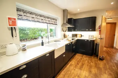 a kitchen with black cabinets and a large window at Ger Yr Afon in Saint Harmon