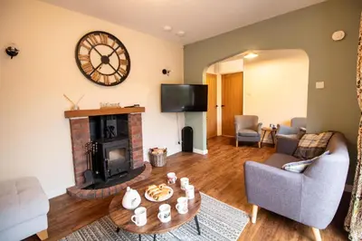 a living room with a fireplace and a clock on the wall at Ger Yr Afon in Saint Harmon
