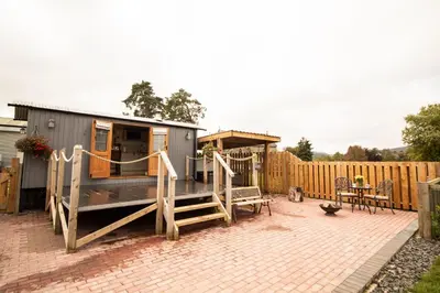 a tiny house with a patio and a fence at Rose in Rhayader