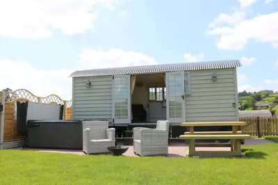 a tiny house with a picnic table and chairs at Sunflower in Saint Harmon