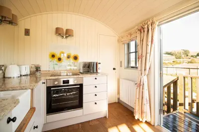 a kitchen with a stove top oven next to a balcony at Sunflower in Saint Harmon