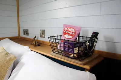 a basket of snacks on a shelf next to a bed at Tulip in Rhayader
