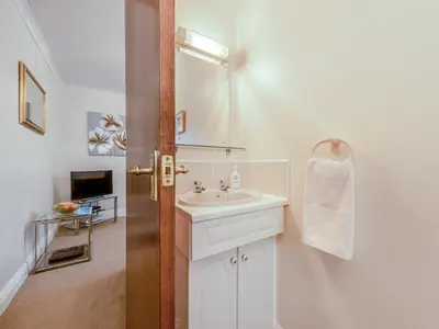 a white bathroom with a sink and a mirror at Craigfryn in Llanerch-Aeron