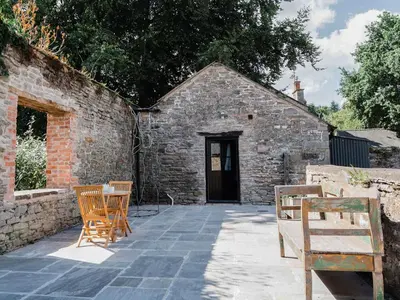 a patio with two chairs and a building at Blackrock Barn in Clifford