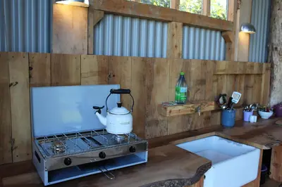 a kitchen with a stove with a tea kettle on it at The Edwardian Caravan 'Dora' in Lampeter