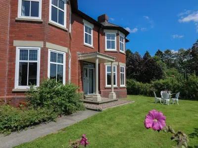 a brick house with a yard with a pink flower at Tirallen in Llanwrda