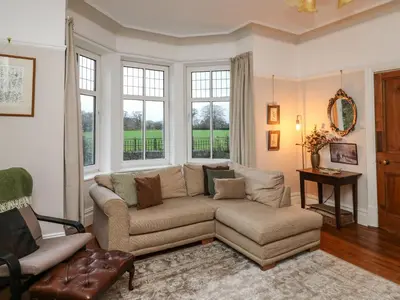 a living room with a couch and a chair and windows at Tirallen in Llanwrda