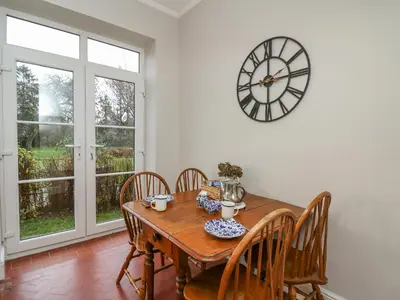 a dining room with a wooden table and a clock on the wall at Tirallen in Llanwrda