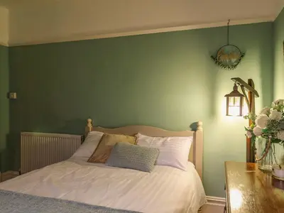 a bedroom with a bed with a green wall at Tirallen in Llanwrda