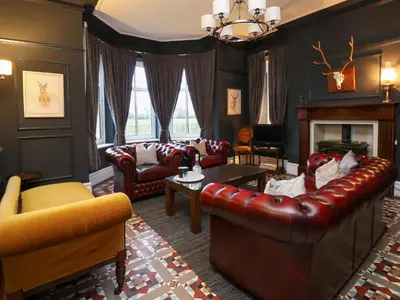 a living room with leather furniture and a fireplace at Tirallen in Llanwrda
